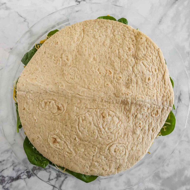 Overhead view of process shot 6 - place the third tortilla in the pan and trim edges if desired.