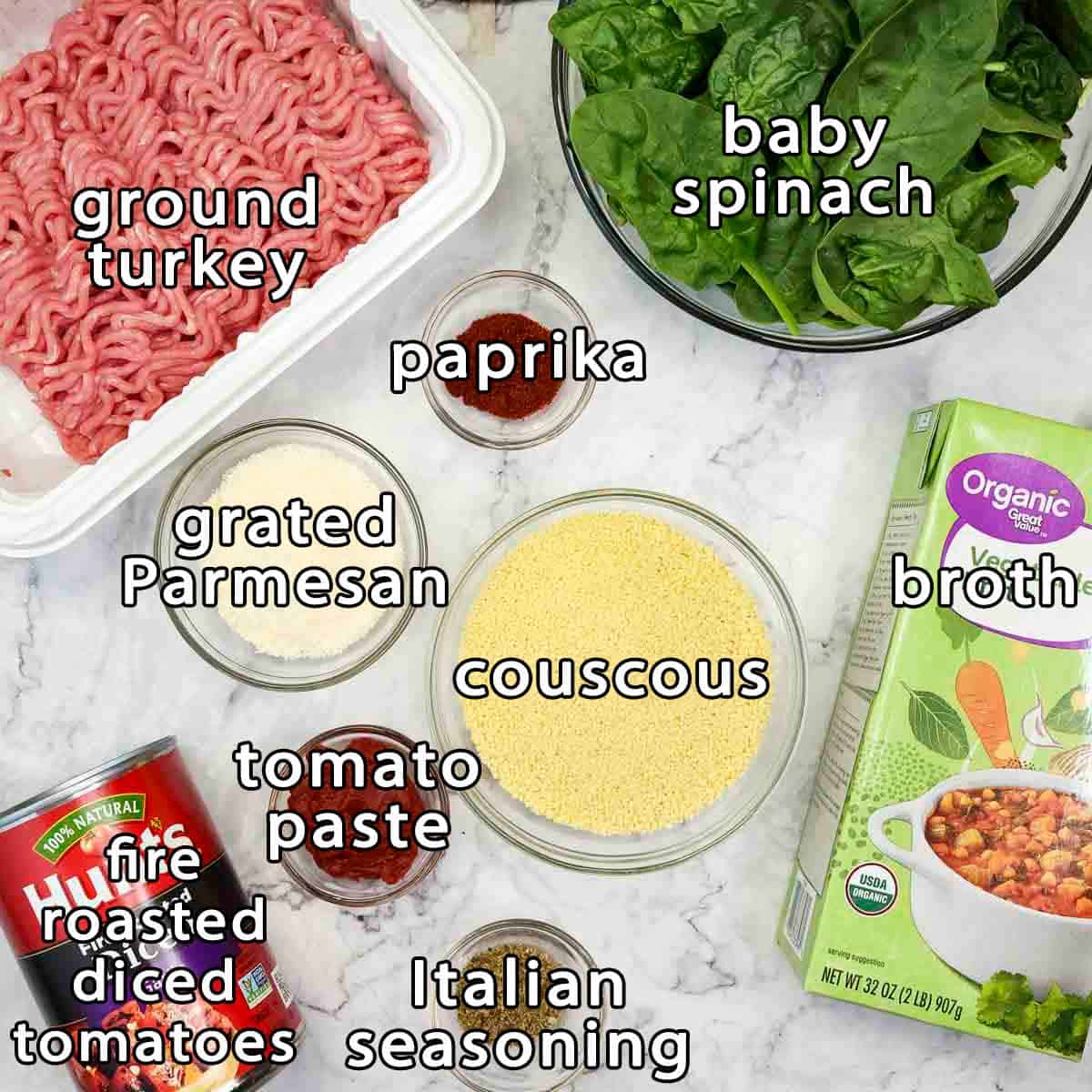 Overhead shot of ingredients - ground turkey, grated parmesan, paprika, baby spinach, couscous, broth, tomato paste, italian seasoning, and fire roasted diced tomatoes.