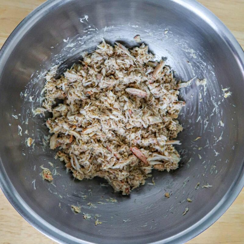 Overhead view of process shot 1 - place imitation crab in a food processor and pulse a few times. Place the crab, egg, bread crumbs, mayonnaise, Old Bay spice, lemon juice, onion powder, and pepper in a large bowl.