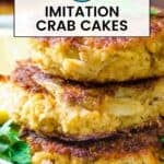 Side shot of fake crab cakes stacked on a white plate with lemon slices and fresh herbs on the side.