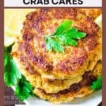Close up shot of fake crab cakes stacked on a bed of lemon slices garnished with fresh herbs.