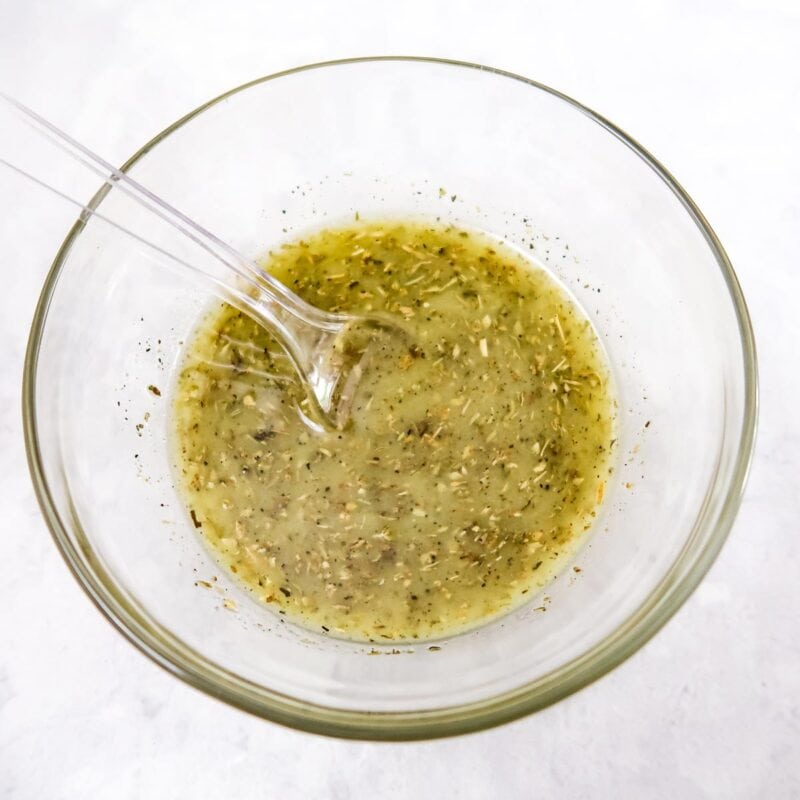 Overhead view of process shot 1 - mix the lemon juice, olive oil, oregano, salt, and pepper in a bowl.