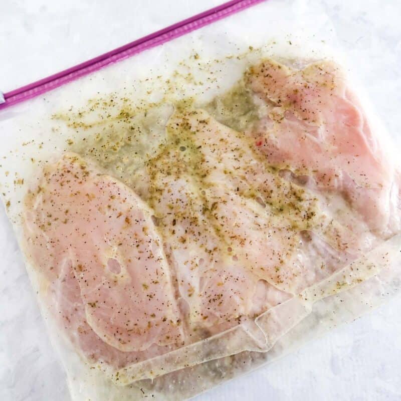 Overhead view of process shot 2 - pour the marinade into a large ziplock bag and add the chicken breasts. Close the bag and squeeze most of the air out and coat the chicken. Place the bag in the fridge for 1-2 hours.