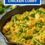 Close up side shot of chicken curry in a cast iron skillet with fresh herbs on the side.