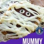 Side shot of mummy cookies laying on a brown paper towel.