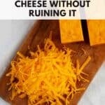 Top down view of shredded cheddar on a wooden cutting board to illustrate how to freeze cheese.