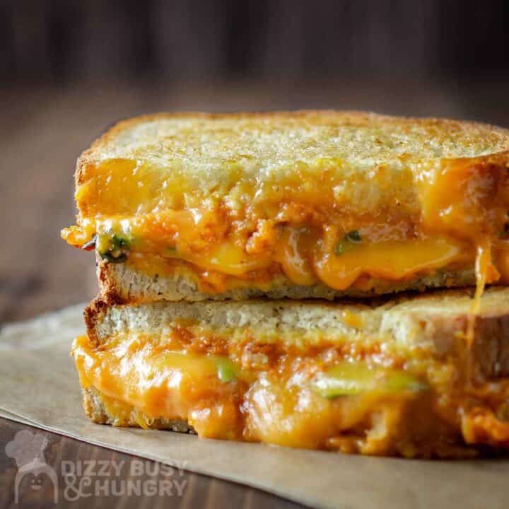 Side shot of two halves of pumpkin grilled cheese stacked on a piece of wax paper.