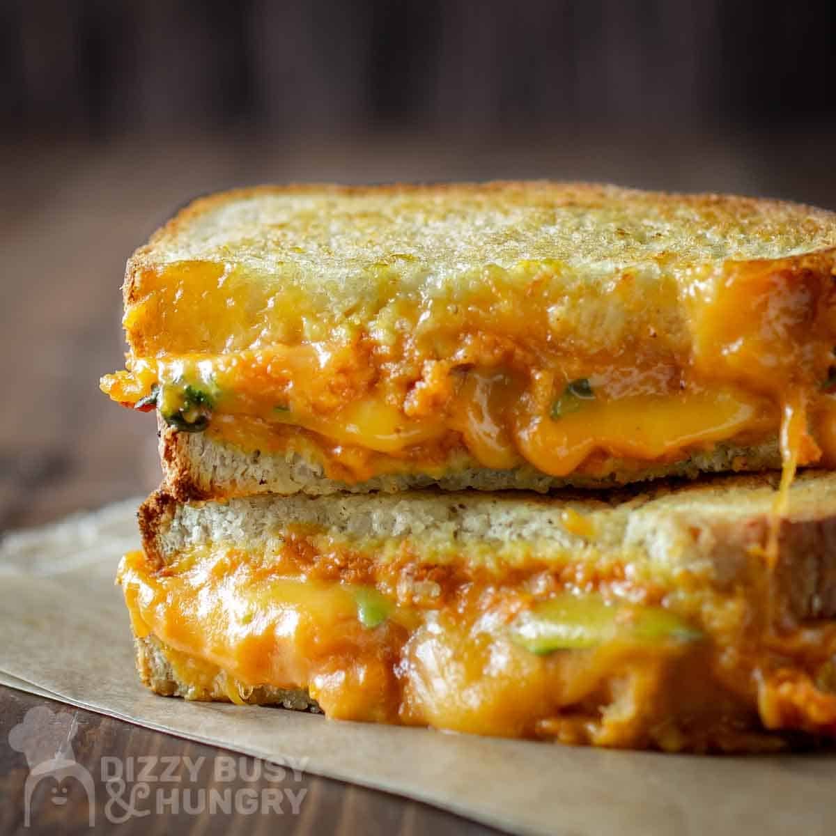 Side shot of two halves of pumpkin grilled cheese stacked on a piece of wax paper.