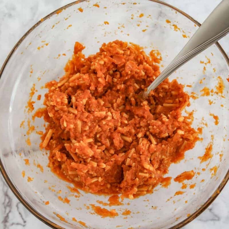 Overhead view of process shot 1 - in a medium bowl, combine the pumpkin, shredded cheese, salt, chili powder, and paprika.