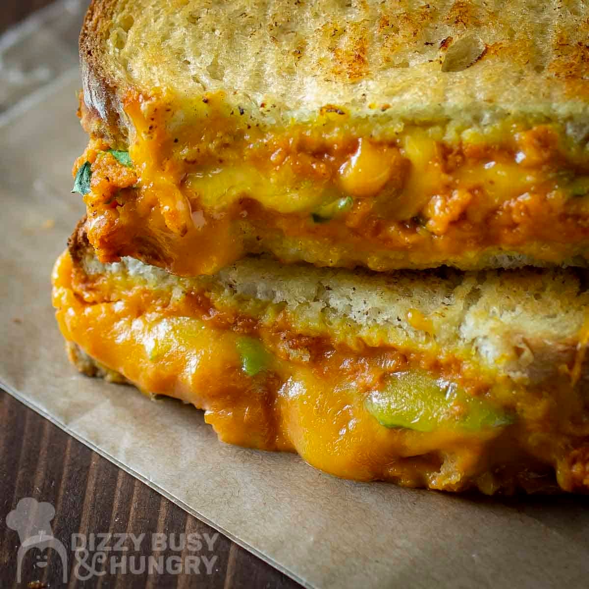 Side shot of two halves of pumpkin grilled cheese stacked on a piece of wax paper.