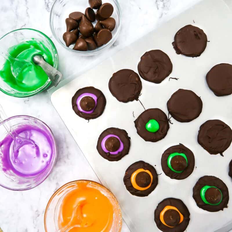Overhead view of process shot 4 - Remove the chocolate covered rounds from the refrigerator. Drop a dollop of icing to the center of each, then press down with a chocolate kiss so that the excess icing forms a ring around the bottom.