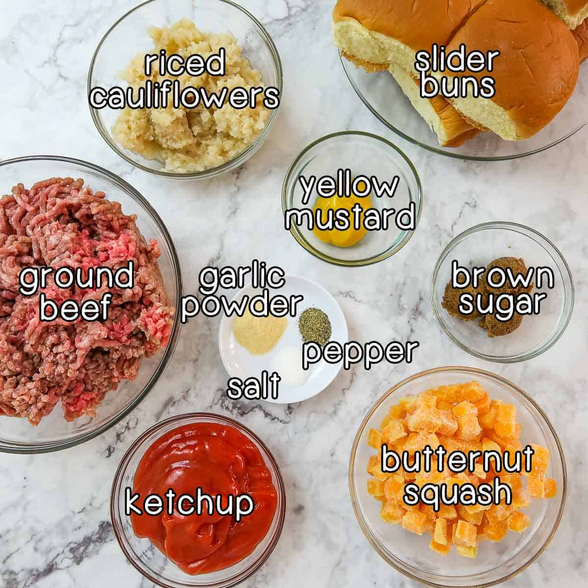 Overhead view of ingredients - slider buns, riced cauliflowers, yellow mustard, brown sugar, ground beef, ketchup, butternut squash, garlic powder, salt, and pepper.