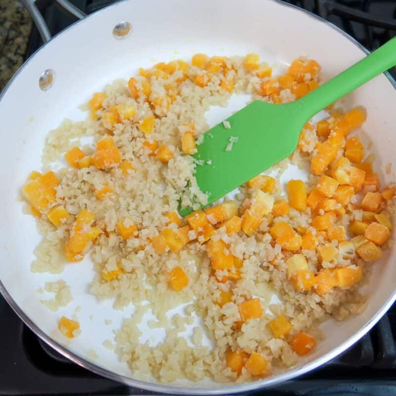 Overhead view of process shot 1 - add olive oil to a skillet and heat over medium high heat. Add the cauliflower and squash and cook until they begin to get soft.