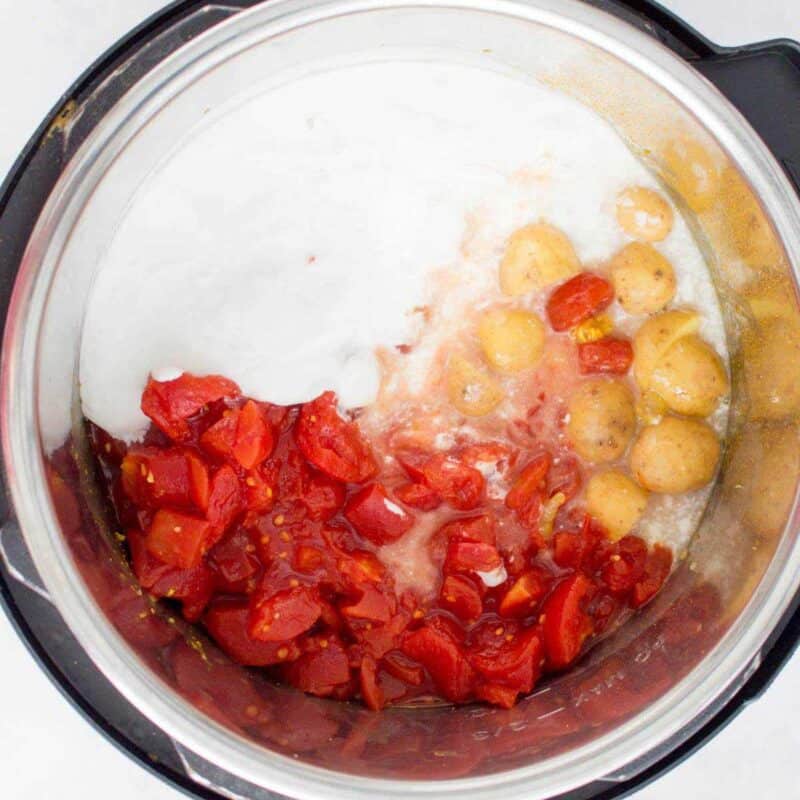 Overhead view of process shot 4 - add in the diced tomatoes, coconut milk, and potatoes plus ¼ cup of water.