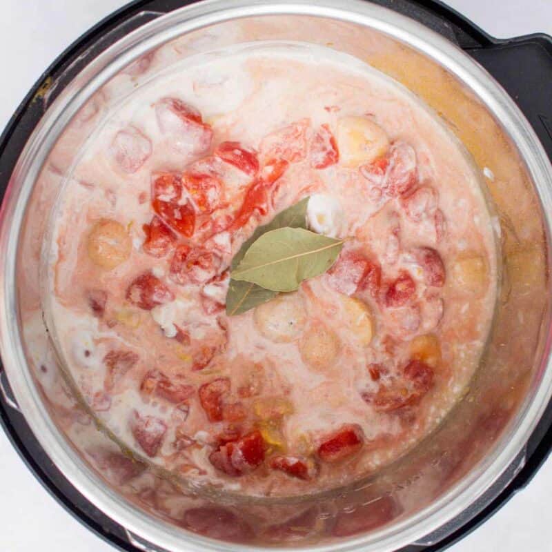 Overhead view of process shot 5 - lightly mix the top layer without disturbing the layer of chicken below. Add the bay leaf and cook under pressure for 4 minutes.