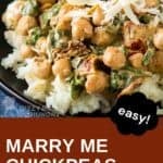 Close up shot of marry me chickpeas and spinach on a bed of rice garnished with shaved parmesan on a black plate.