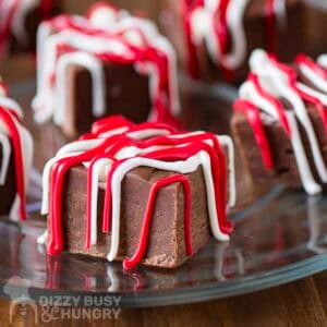 Side shot of multiple pieces of fudge drizzled with red and white melted chocolate.