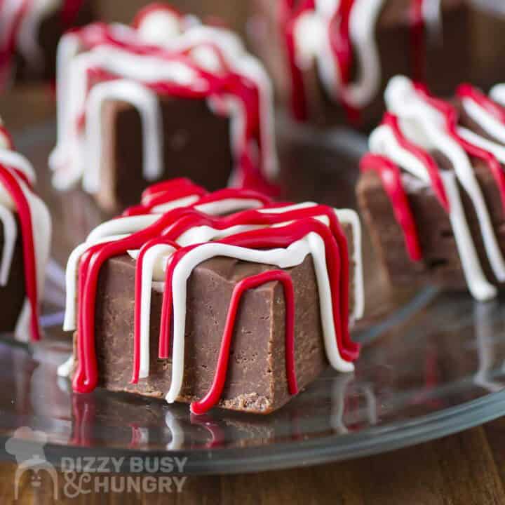 Side shot of multiple pieces of fudge drizzled with red and white melted chocolate.