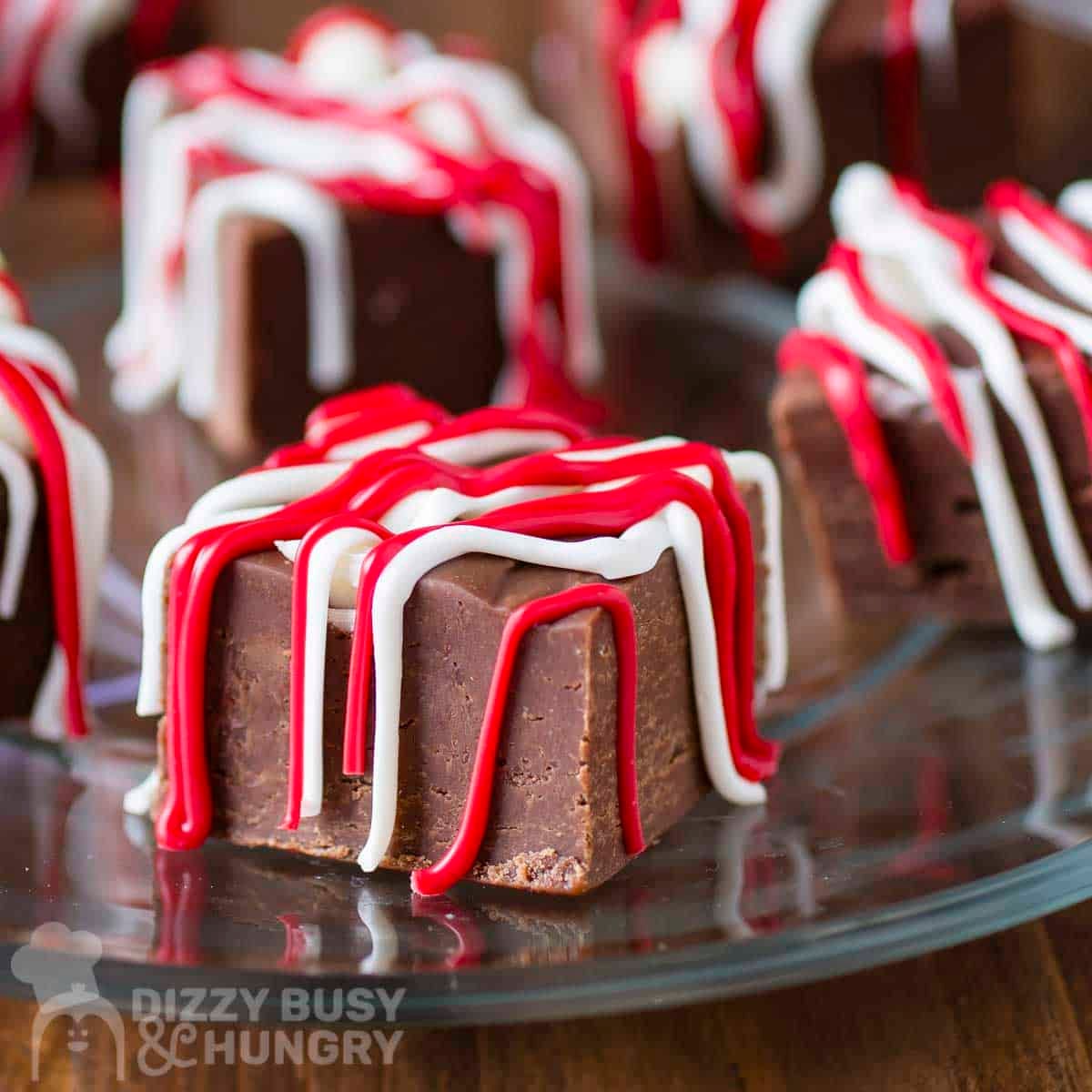 Side shot of multiple pieces of fudge drizzled with red and white melted chocolate.